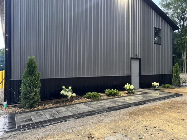 A new paver walkway with a charcoal border running along a pole barn.